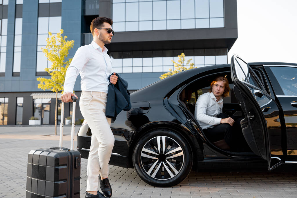 Businessmen with black suitcase traveling by premium car