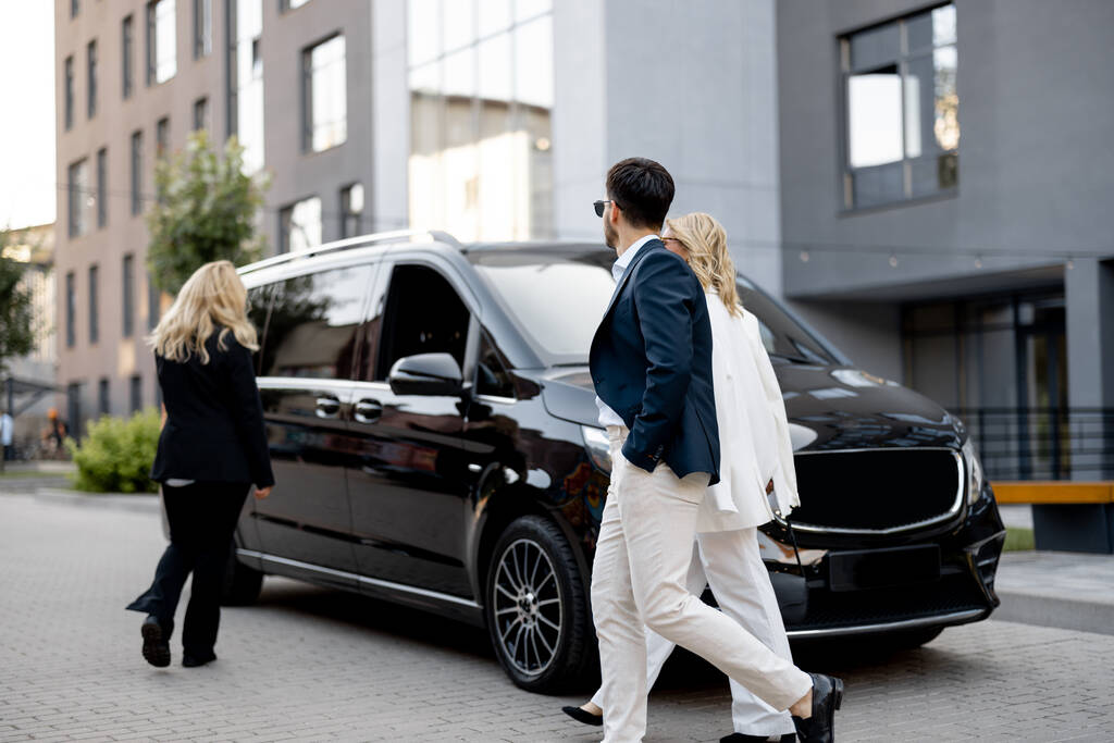  Business people walk towards minivan taxi