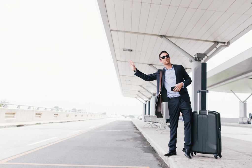 Attractive businessman calling a taxi at the airport