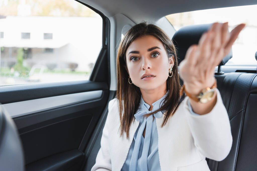 Lady pointing hand while sitting in car back seat