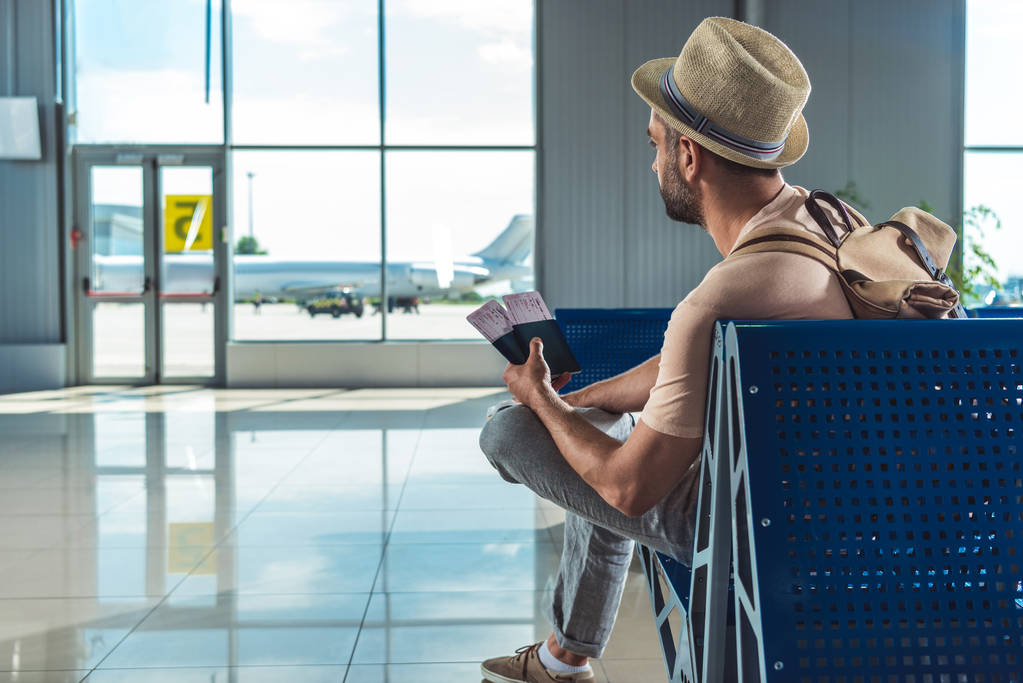 Traveller sitting with passport and tickets at airport