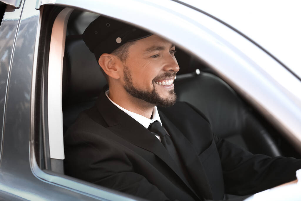 Handsome chauffeur driving luxury car