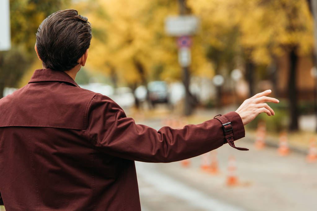 Back view of man catching a taxi