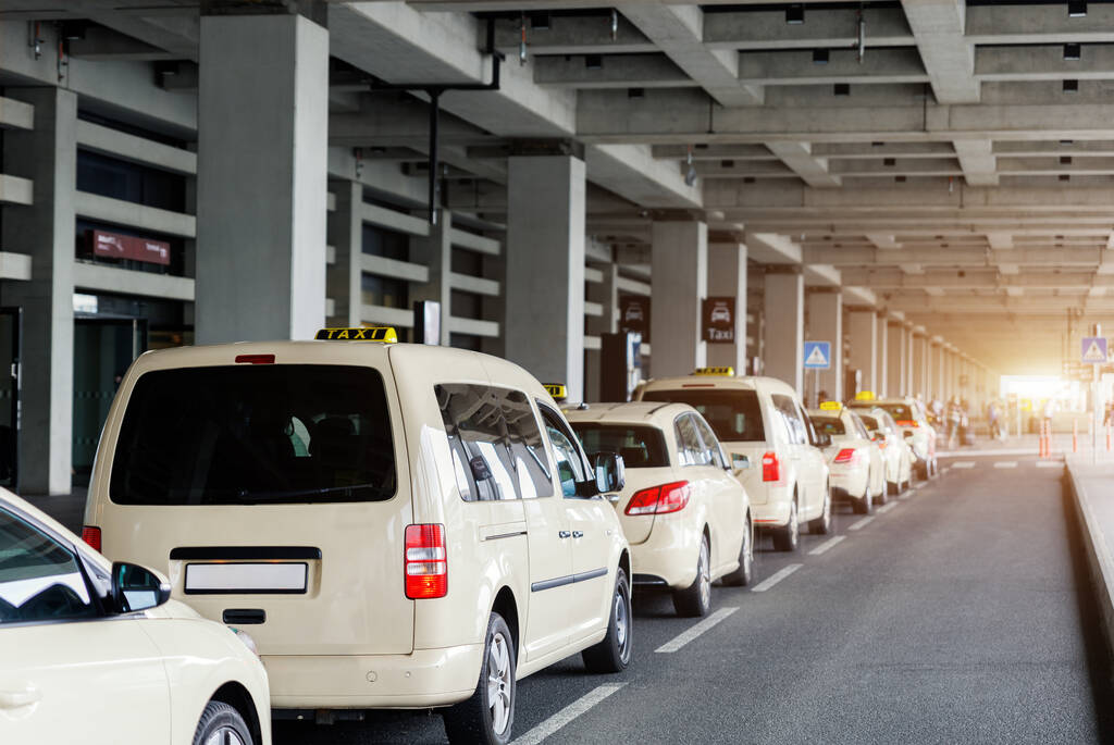 Taxi car Queue yellow taxi symbol  on roof stand waiting at parking of airport terminal or railway station Under Concrete Structure Transportation Hub. Urban street transportation comfort service.